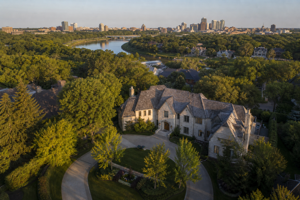 Cinematic aerial view of luxury riverside estate overlooking city skyline at golden hour